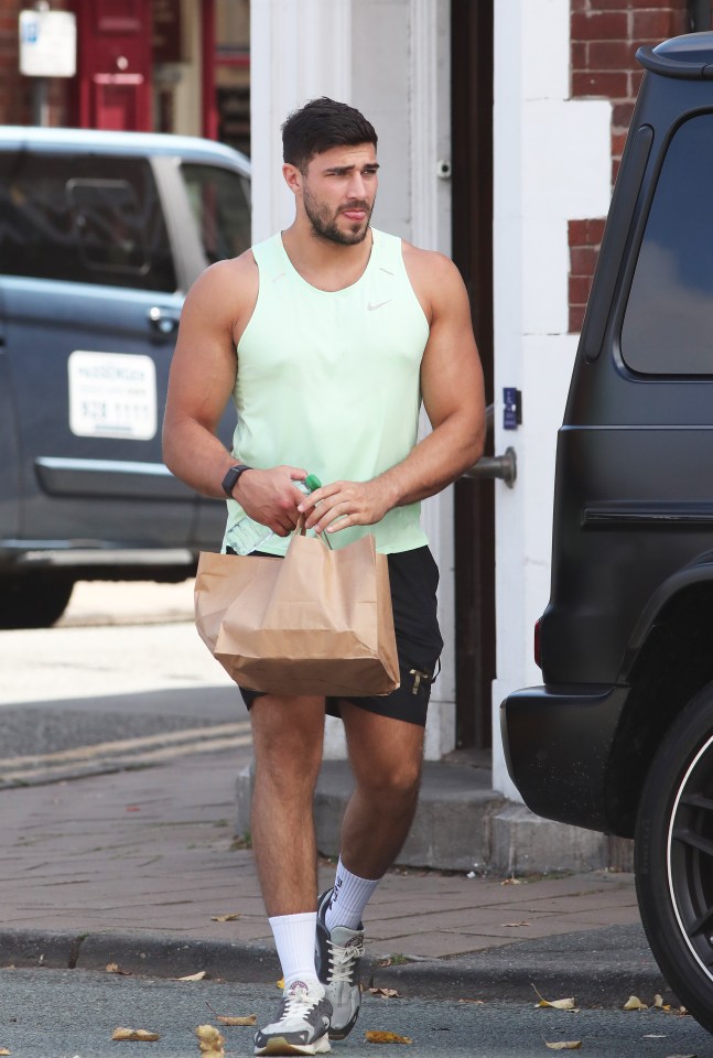 a man in a green nike tank top carrying a brown bag