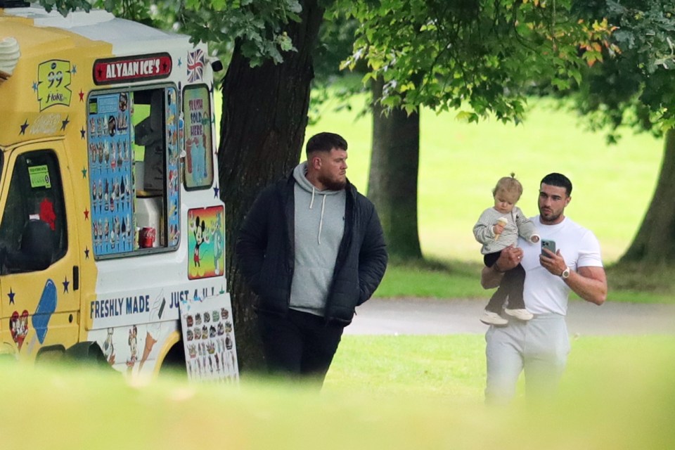 a man holding a child in front of an ice cream truck that says mylan ice