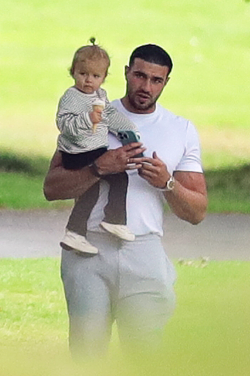 a man is holding a baby on his shoulders while looking at his phone .