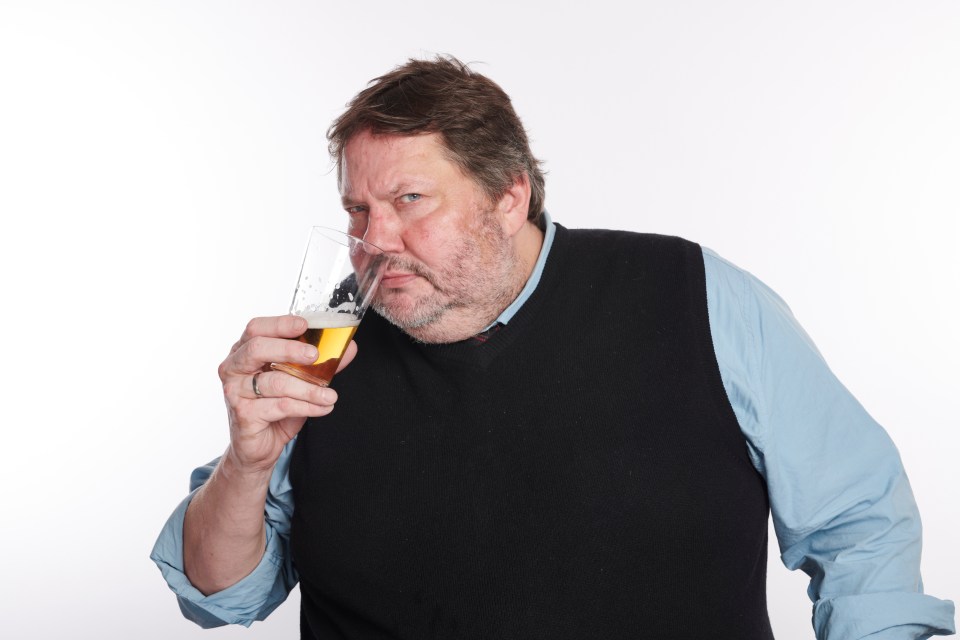 a man with a beard is drinking a glass of beer