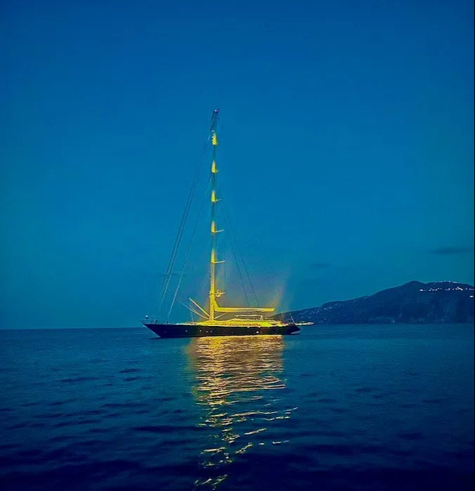 a sailboat is lit up in the middle of the ocean