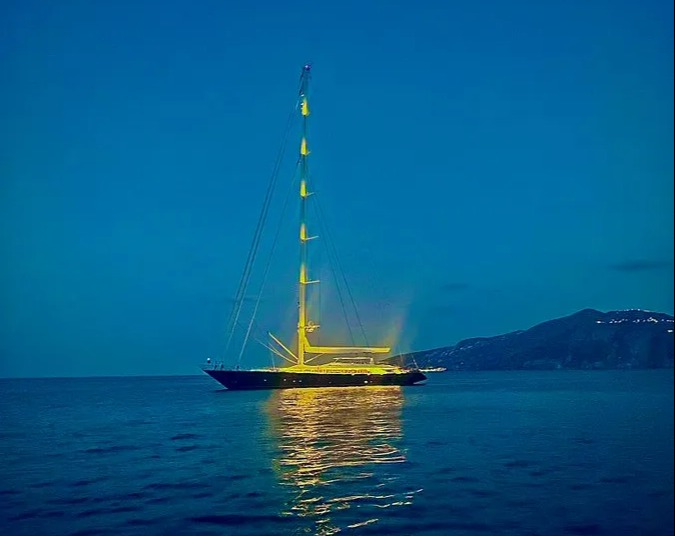 a sailboat is lit up in the middle of the ocean