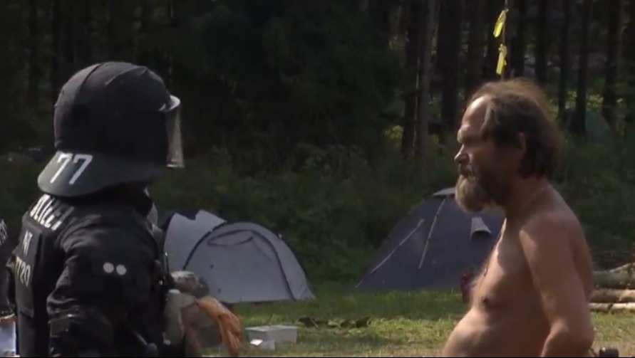 a man without a shirt is talking to a police officer