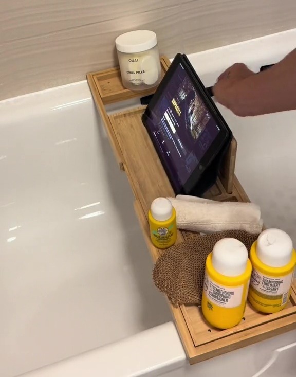 a person using a tablet in a bathtub next to a container that says okay