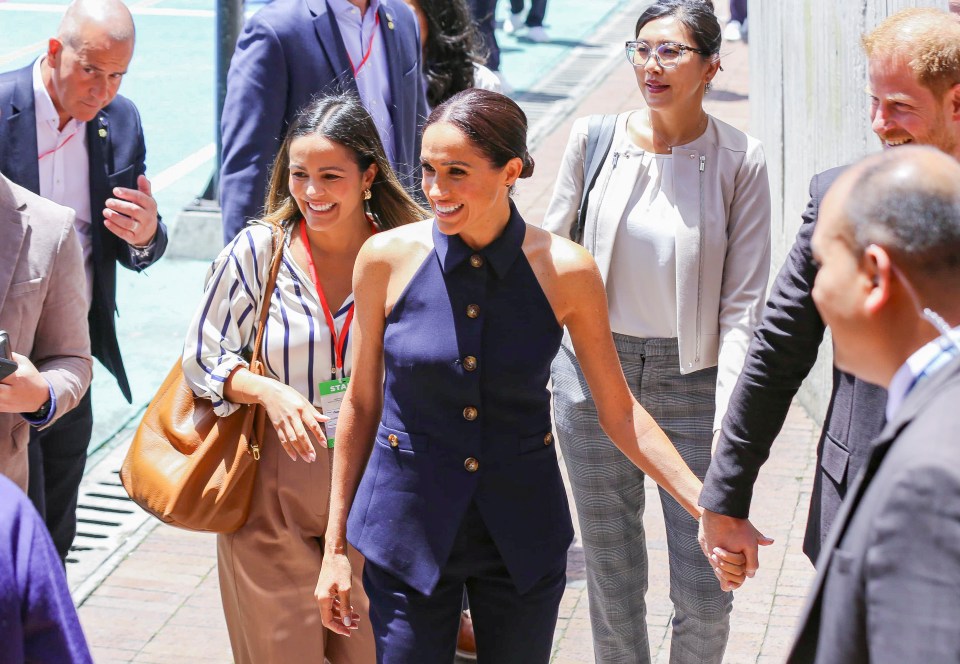 Harry and Meghan holding hands later on in the day as they appear at a local children's school