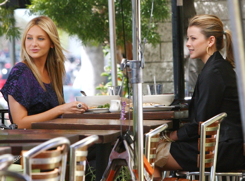 two women sit at a table with plates of food in front of them