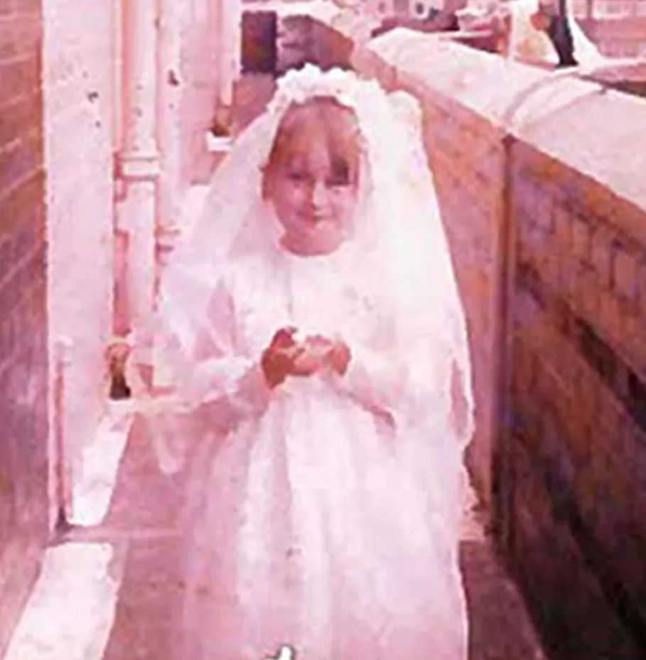 a little girl in a white dress is standing on a balcony