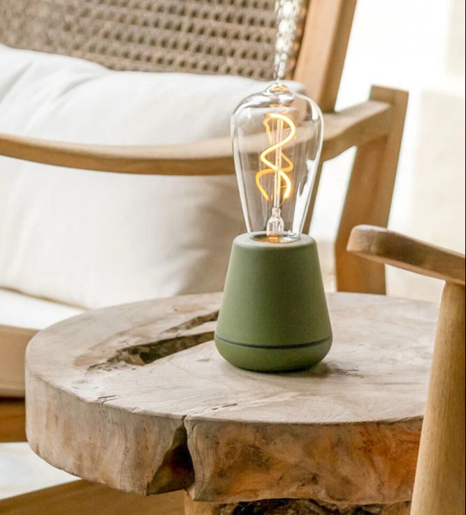 a green lamp sits on a wooden table next to a chair