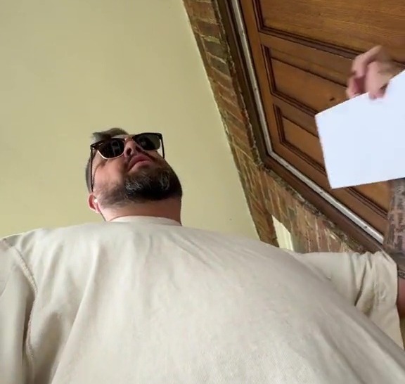 a man wearing sunglasses is holding an envelope in front of a door