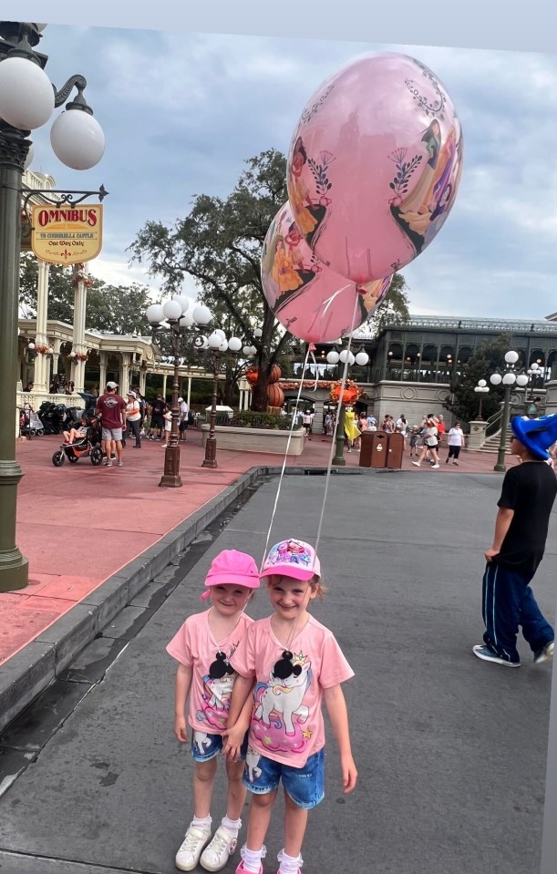 two little girls holding hands in front of a sign that says openbus