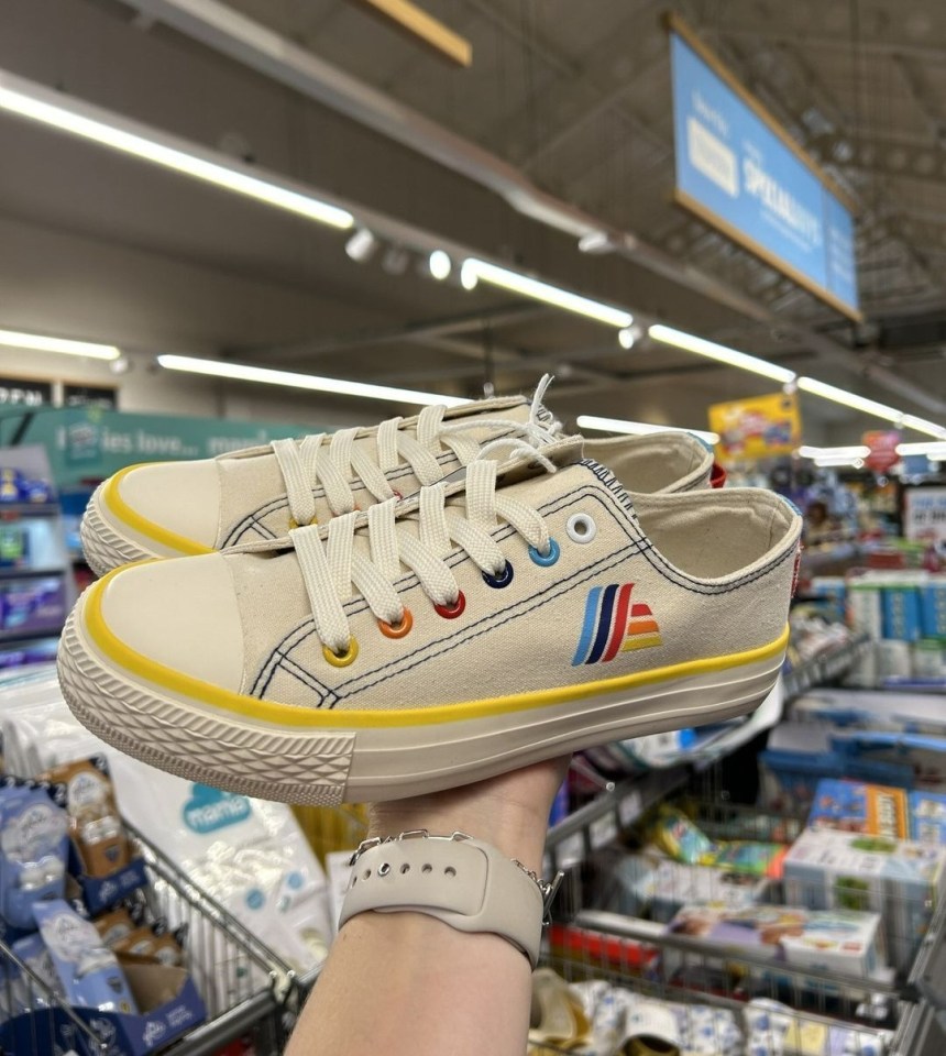 a person is holding a pair of sneakers in a store