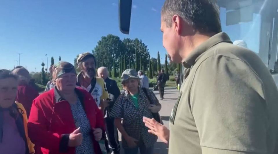 An official speaks to crowds near the buses