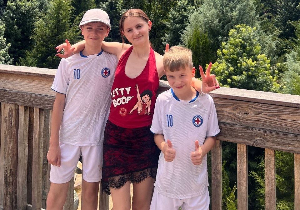 a girl wearing a betty boop shirt stands with two boys in front of a castle