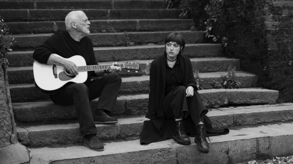 a man playing a guitar next to a woman