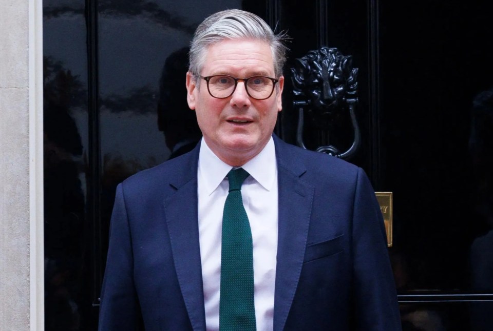 a man in a suit and tie stands in front of a black door with the number 10 on it