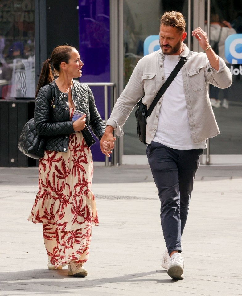 a man and woman are walking down the street holding hands