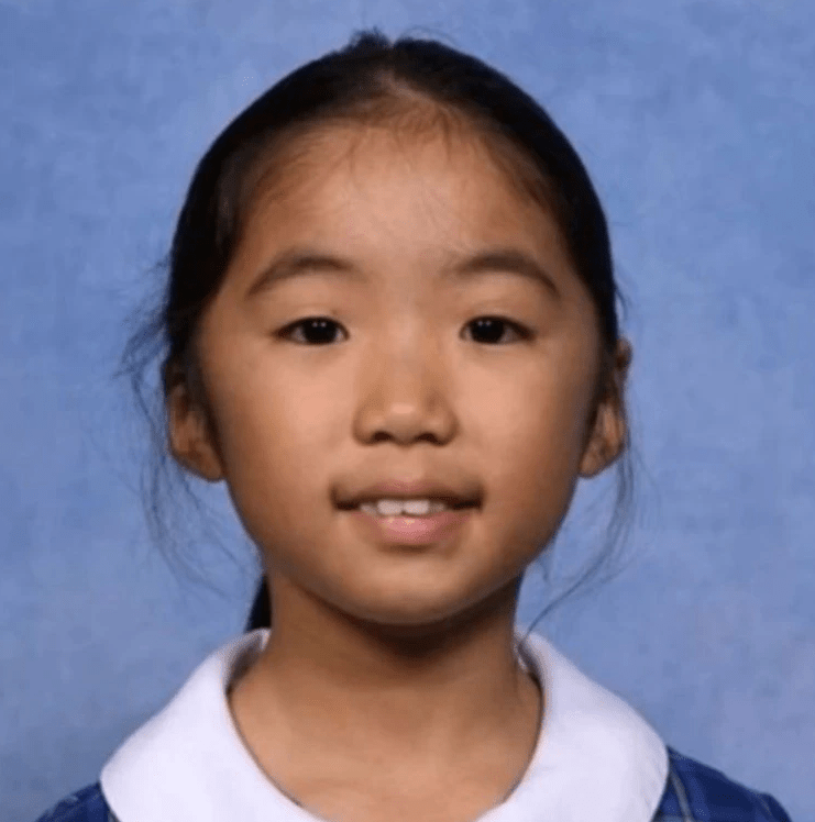 a young girl wearing a blue shirt and white collar smiles for the camera