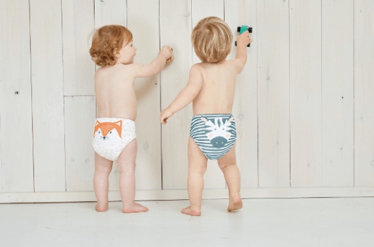 a boy and a girl in diapers are standing next to each other