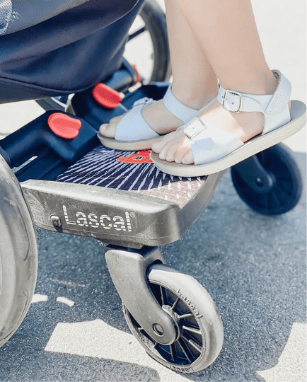 a child sits on a board that says lascal on it