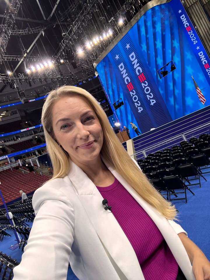 a woman stands in front of a stage that says dnc 2024