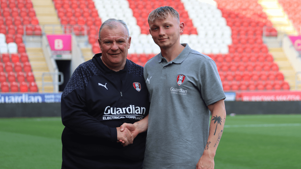 a man wearing a guardian shirt shakes hands with another man