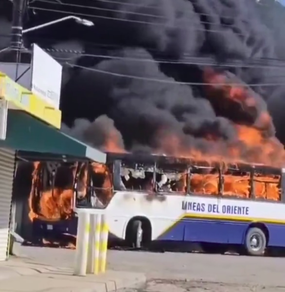 A bus erupts into flames, blocking off a road