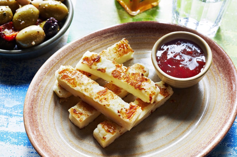 a plate of cheese sticks with a bowl of jam on the side