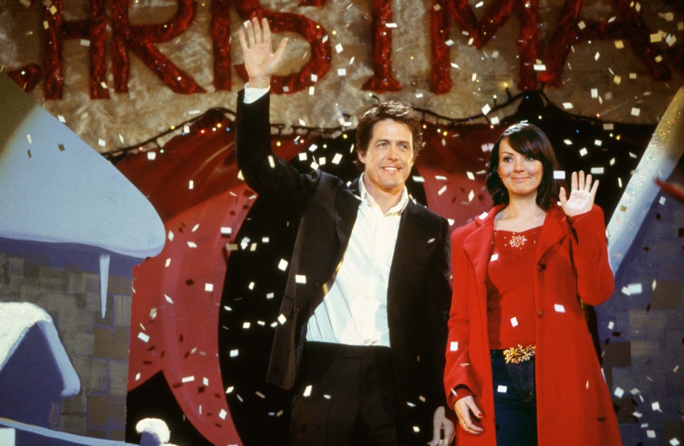 a man and woman are standing in front of a sign that says christmas