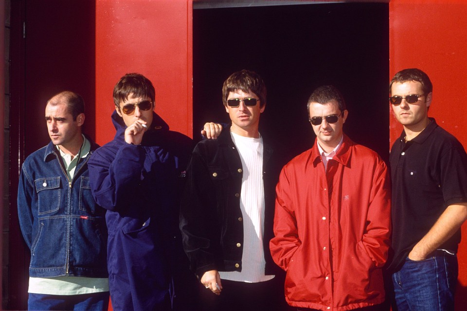 a group of men standing in front of a red wall