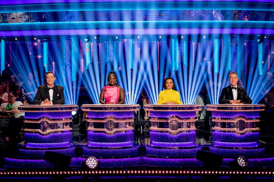 a group of people sitting in front of a stage with purple lights