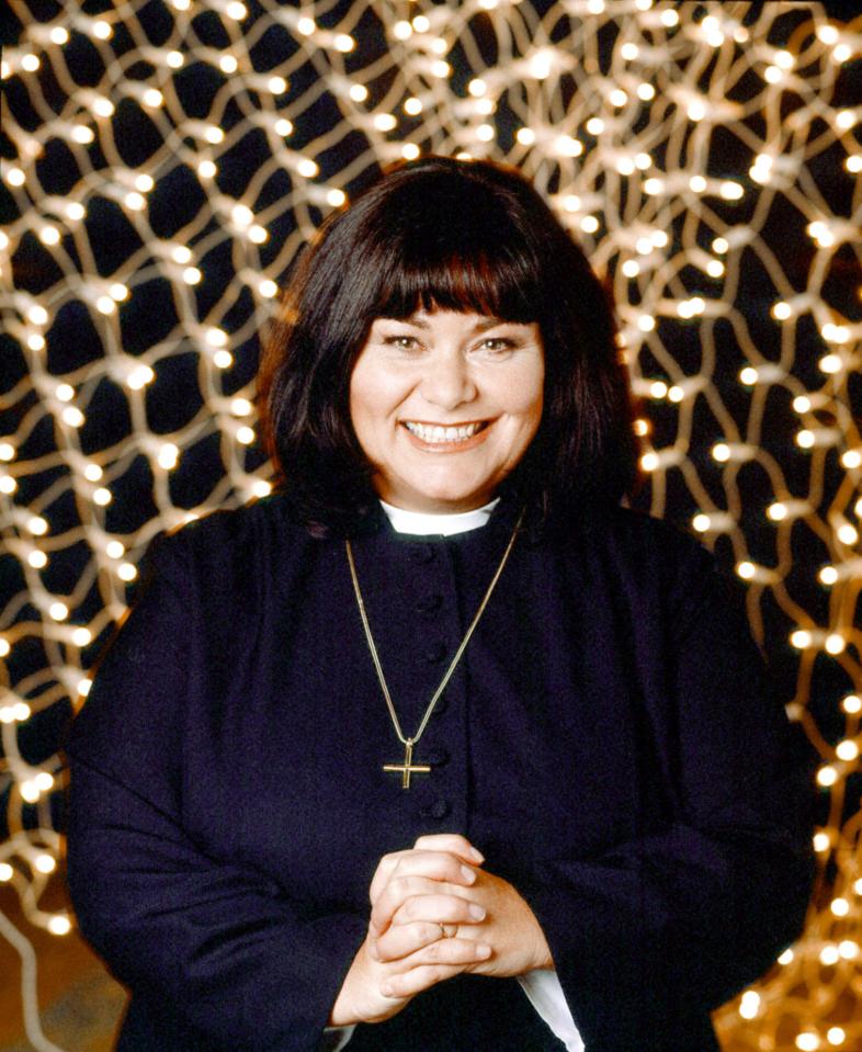 a woman wearing a black jacket and a cross necklace smiles for the camera