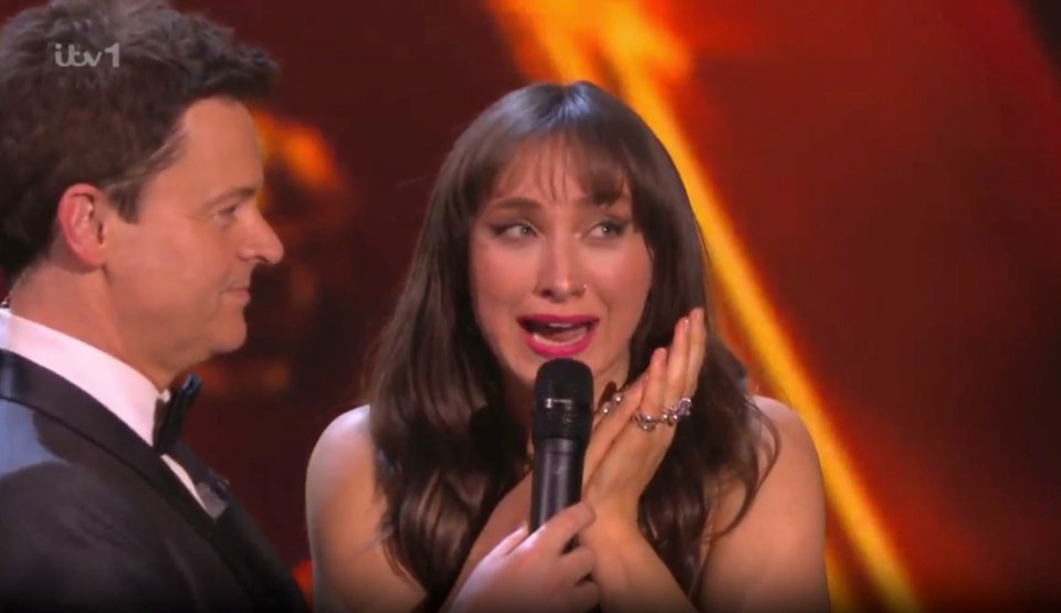 a woman is crying while holding a microphone next to a man in a tuxedo