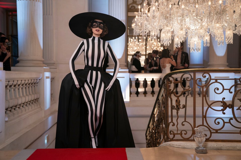 a woman in a black and white striped outfit is standing on a red carpet