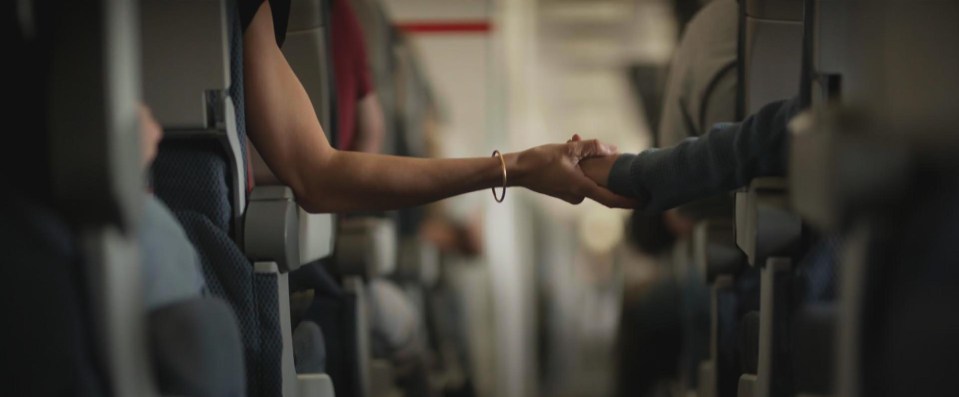 a woman is holding another woman 's hand on an airplane