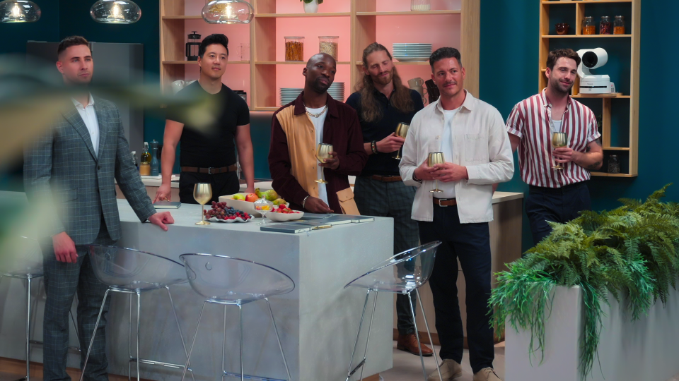 a group of men standing in a kitchen holding wine glasses