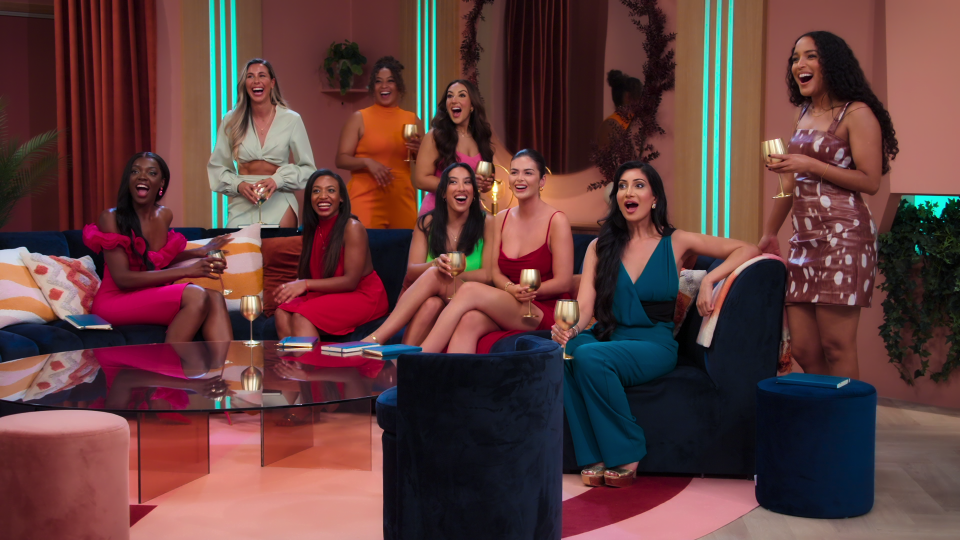 a group of women sitting on a couch holding wine glasses