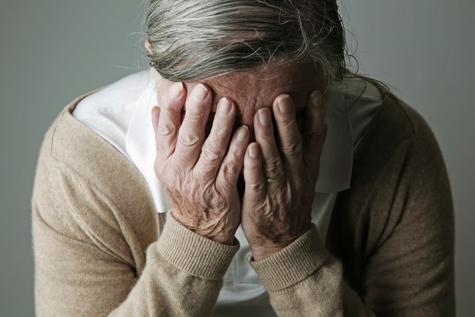 an older woman covering her face with her hands