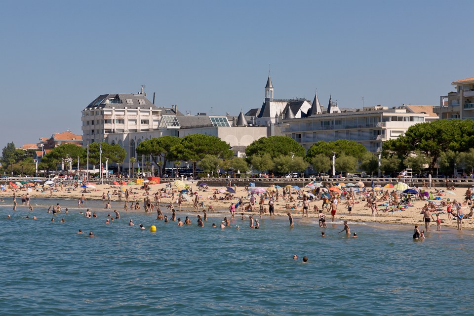 a beach scene with a large building in the background