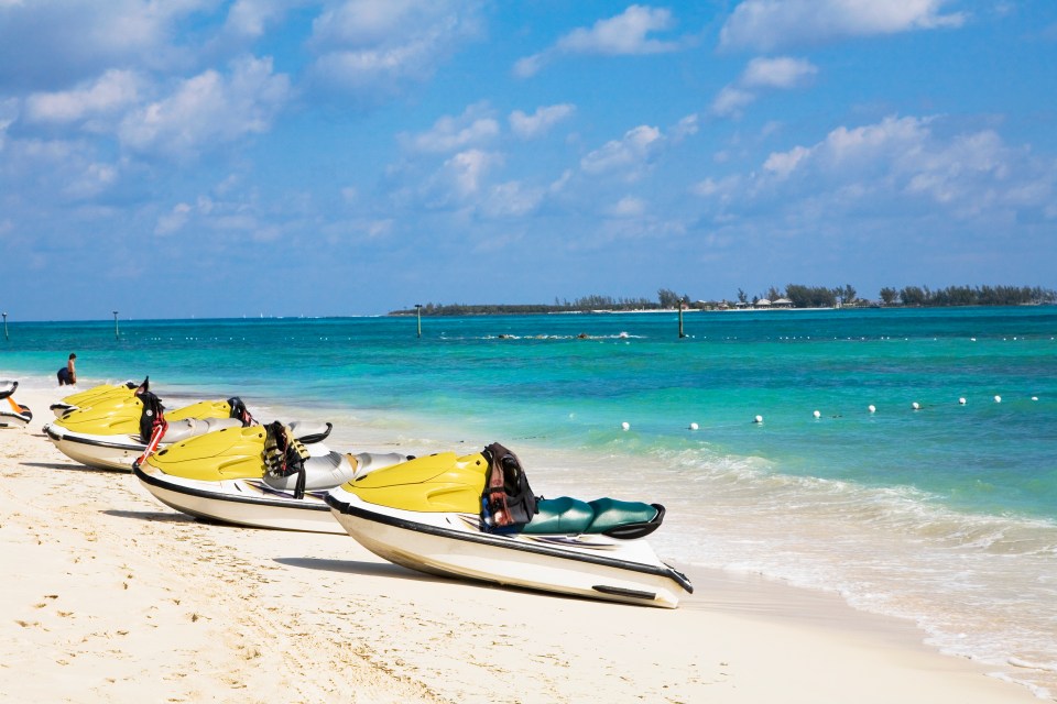 a row of yellow and white jet skis on a beach