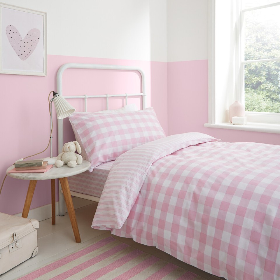 a bed with a pink and white checkered comforter and pillows