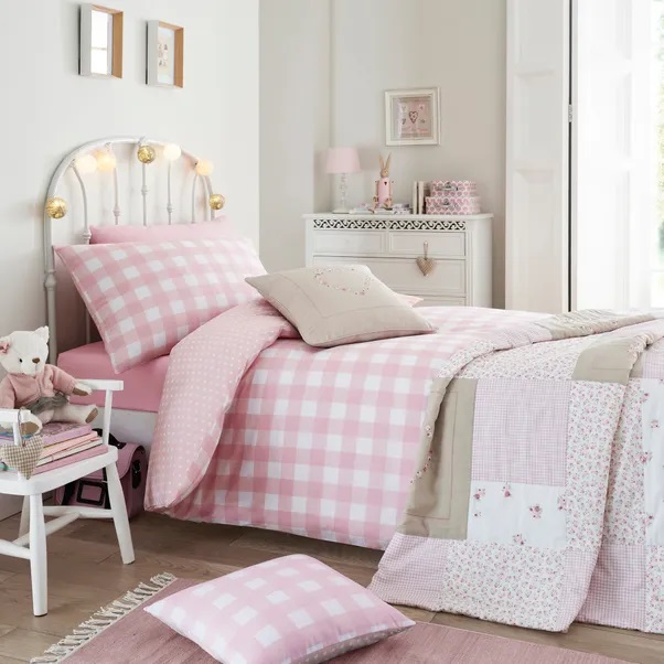 a girl 's bedroom with a pink and white checkered comforter