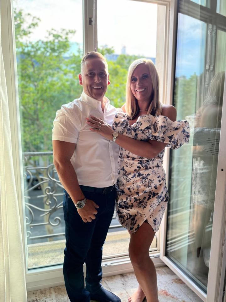 a man and a woman are posing for a picture in front of a window