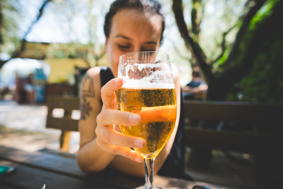 a woman with a tattoo on her arm holds a glass of beer