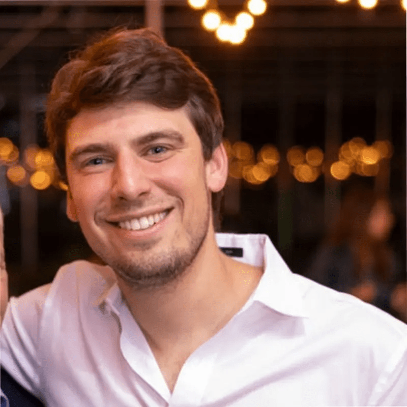 a man in a white shirt smiles for the camera