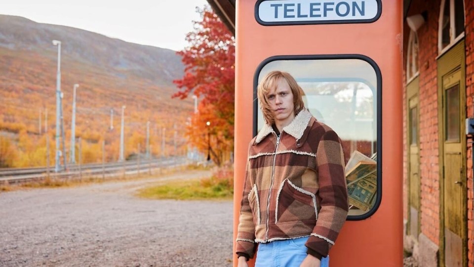 a man stands in front of a phone booth that says telefon