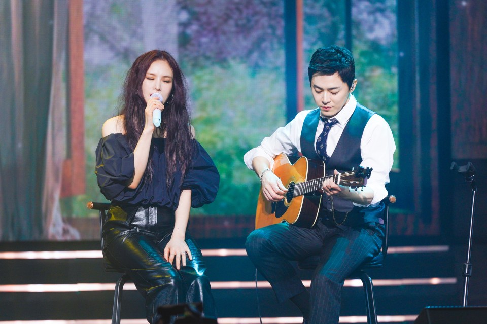 a man playing a guitar next to a woman singing into a microphone