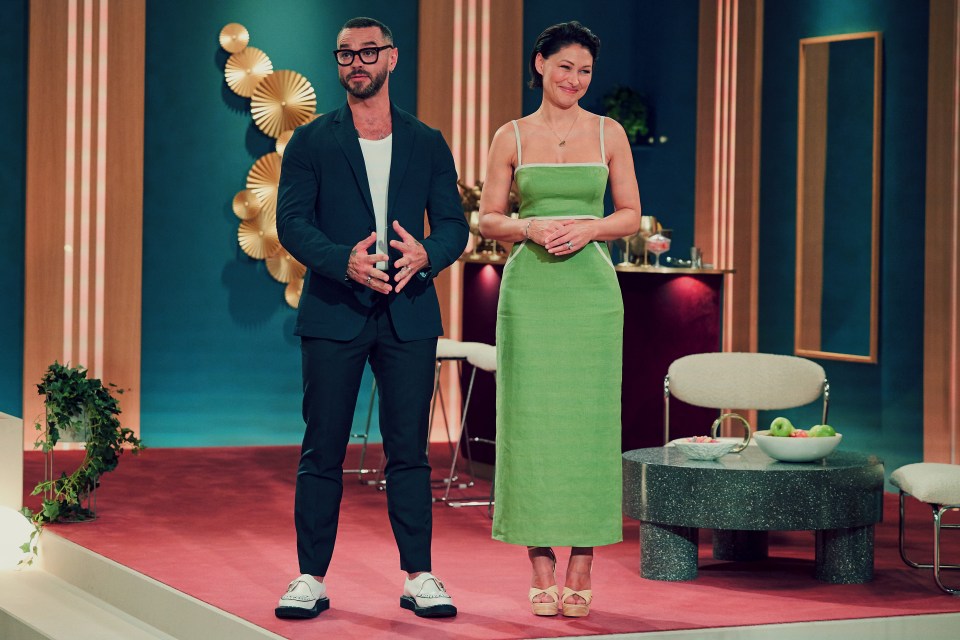 a man in a suit stands next to a woman in a green dress