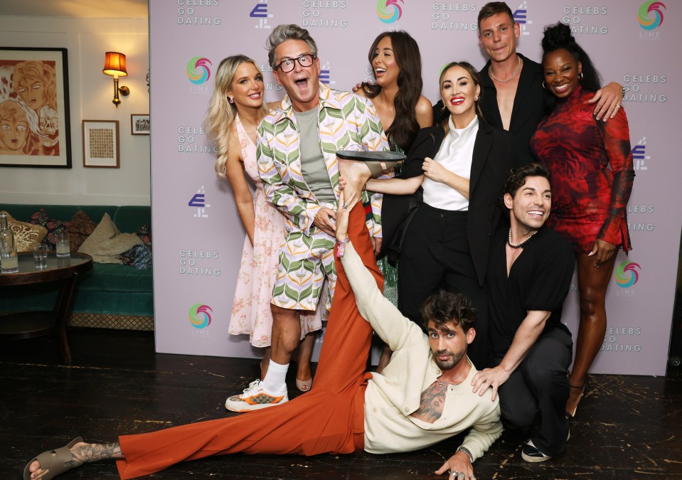 a group of people posing for a picture in front of a wall that says celebs go dating