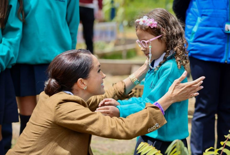 a woman adjusts a little girl 's glasses while wearing a wristband that says ' esperanza '