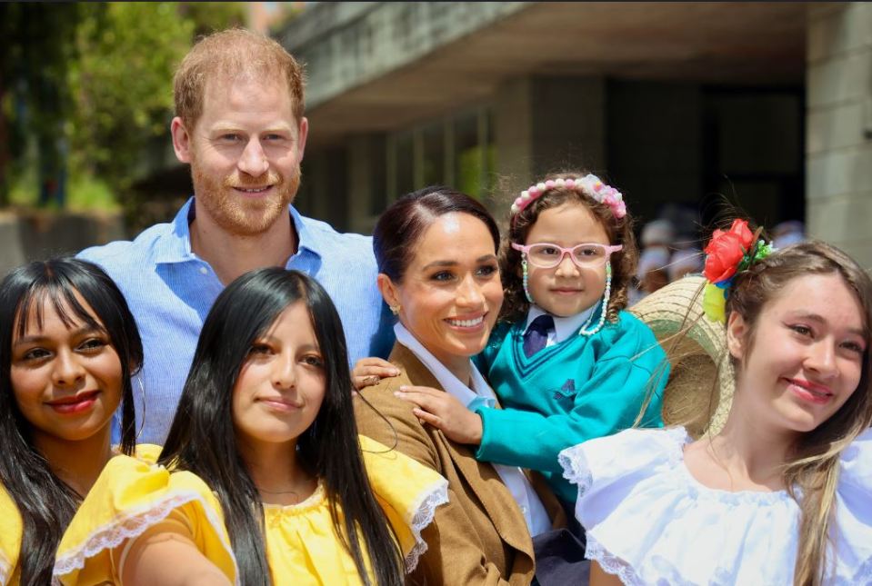 a man in a suit holds hands with a woman in a blue top